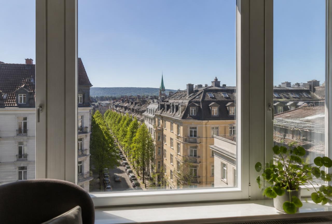 Klare Sicht durch ein frisch gereinigtes Fenster auf Zürcher Dächer und eine Baumallee